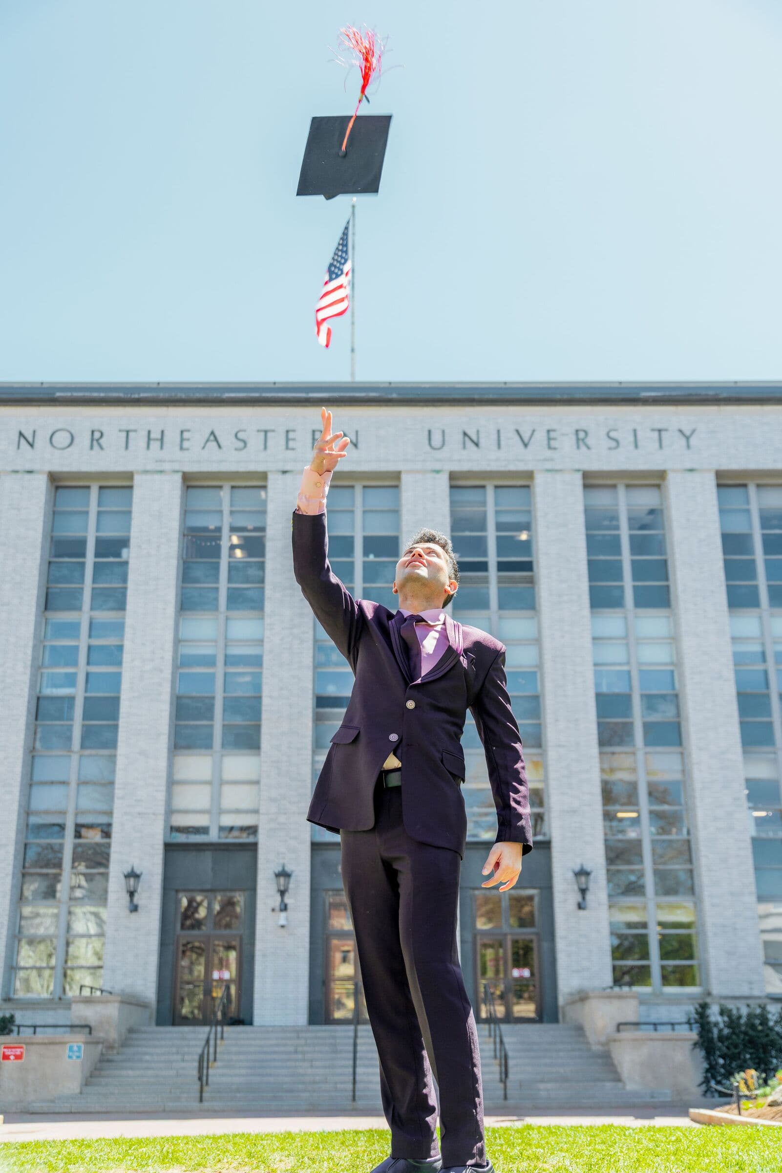 Shayan Menahi tossing his graduation cap outside Northeastern University